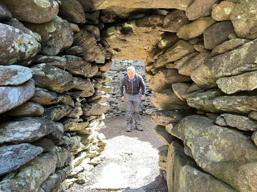Person walking through a narrow stone passageway.